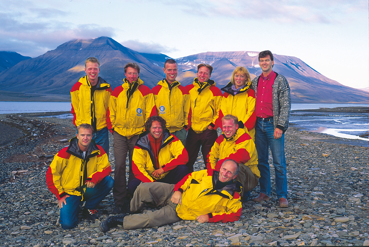 En gruppe med guider og gründer Arne Kristoffersen. Gruppen står på en steinstrand med fjell i bakgrunnen.
